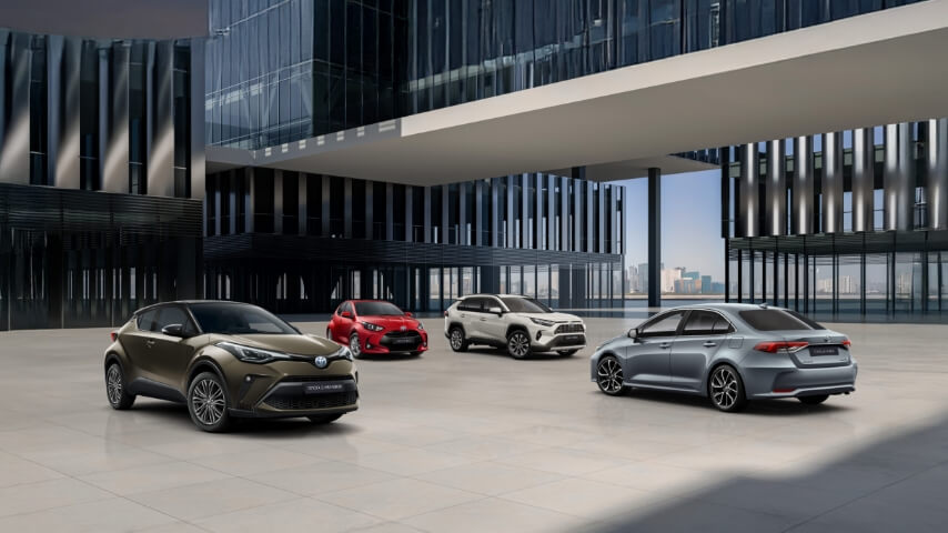 Cztery modele Toyoty zaparkowane na placu między nowoczesnymi budynkami